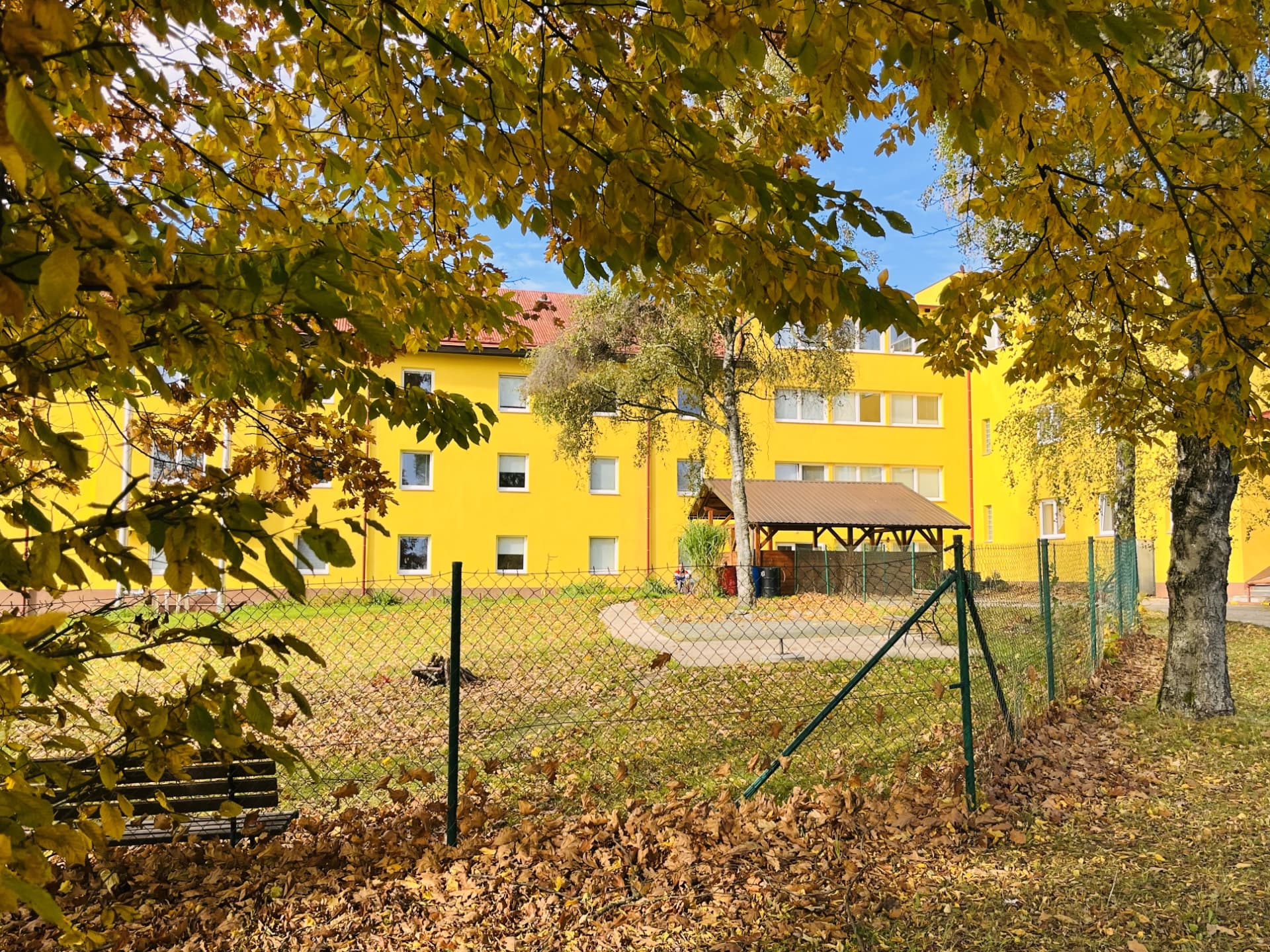 Pohled na budovu sanatoria s lavičkou v popředí