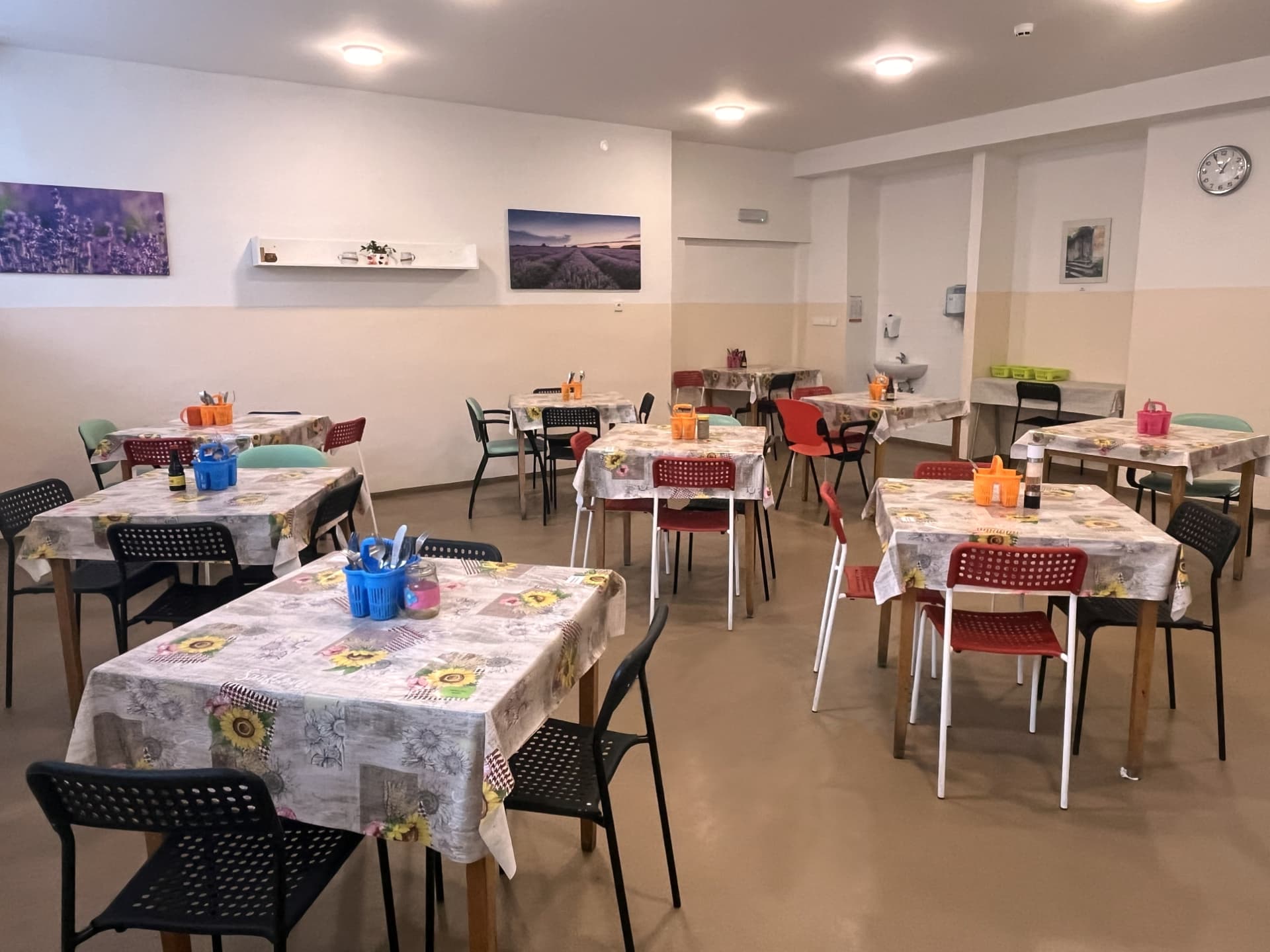 Společná jídelna se stoly a barevnými židlemi